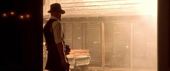 Movie still from “Last Man Standing” (1996), directed by Walter Hill – A man standing in front of a wooden building; Wide shot, Low angle