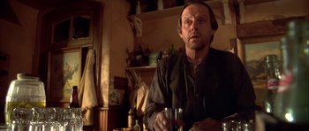 Movie still from “Last Man Standing” (1996), directed by Walter Hill – A man holding a wine glass while sitting at a table; Medium shot, Low angle