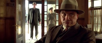 Movie still from “Last Man Standing” (1996), directed by Walter Hill – A man in a suit and a hat is in front of two other men; Medium shot, Low angle