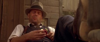 Movie still from “Last Man Standing” (1996), directed by Walter Hill – A man wearing a hat is holding an apple; Medium shot, Overhead angle