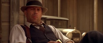 Movie still from “Last Man Standing” (1996), directed by Walter Hill – A man wearing a hat , vest , and tie holding a book; Close Up shot, Over the shoulder angle