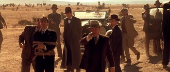 Movie still from “Last Man Standing” (1996), directed by Walter Hill – A group of men standing next to each other in front of an antique car; Medium shot, Over the shoulder angle