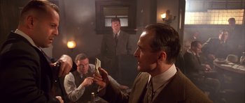 Movie still from “Last Man Standing” (1996), directed by Walter Hill – A group of people sitting around a table; Medium shot, Low angle