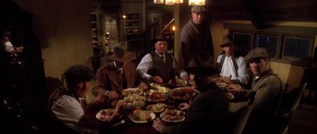 Movie still from “Last Man Standing” (1996), directed by Walter Hill – A group of men sitting at a table with plates of food on it; Wide shot, High angle