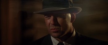 Movie still from “Last Man Standing” (1996), directed by Walter Hill – A person wearing a suit and a hat; Close Up shot, Low angle