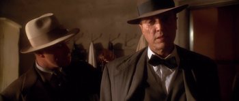 Movie still from “Last Man Standing” (1996), directed by Walter Hill – A man in a suit and hat smoking a cigarette; Close Up shot, Over the shoulder angle