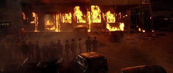 Movie still from “Last Man Standing” (1996), directed by Walter Hill – A group of men standing in front of a burning building; Extreme Wide shot, High angle