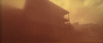 Movie still from “Last Man Standing” (1996), directed by Walter Hill – A building with a balcony on the top of it in the fog; Extreme Wide shot, Low angle