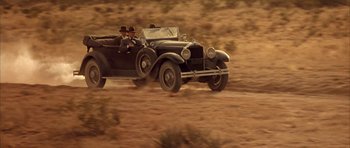 Movie still from “Last Man Standing” (1996), directed by Walter Hill – Two men driving a vintage car in the desert; Wide shot, Low angle