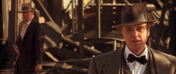 Movie still from “Last Man Standing” (1996), directed by Walter Hill – A man in a suit and hat standing in front of rubble; Close Up shot, Over the shoulder angle