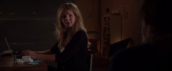 Movie still from “Fifty Shades of Grey” (2015), directed by Sam Taylor-Johnson – A woman sitting in a chair in a dark room; Medium shot, Over the shoulder angle