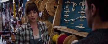 Movie still from “Fifty Shades of Grey” (2015), directed by Sam Taylor-Johnson – A woman standing in front of a rack of ropes; Medium shot, Over the shoulder angle