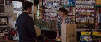 Movie still from “Fifty Shades of Grey” (2015), directed by Sam Taylor-Johnson – A woman holding a brown paper bag in front of a man; Medium shot, Over the shoulder angle
