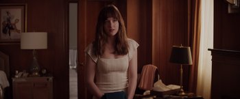 Movie still from “Fifty Shades of Grey” (2015), directed by Sam Taylor-Johnson – A woman standing in front of a wooden wall; Medium shot, Over the shoulder angle