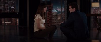 Movie still from “Fifty Shades of Grey” (2015), directed by Sam Taylor-Johnson – A woman and a man sitting on the ground; Medium shot, High angle