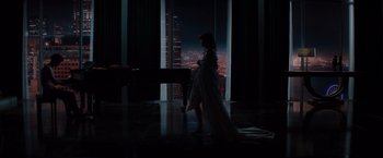 Movie still from “Fifty Shades of Grey” (2015), directed by Sam Taylor-Johnson – A woman standing in front of an open window at night; Wide shot, High angle