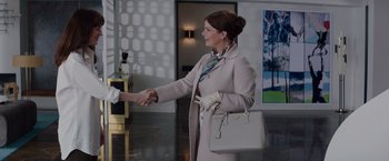 Movie still from “Fifty Shades of Grey” (2015), directed by Sam Taylor-Johnson – A woman in a white coat shaking hands with a man in a gray coat; Medium shot, Over the shoulder angle