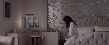 Movie still from “Fifty Shades of Grey” (2015), directed by Sam Taylor-Johnson – A woman sitting in a chair in front of a mirror in a room; Medium shot, High angle