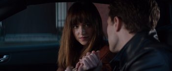 Movie still from “Fifty Shades of Grey” (2015), directed by Sam Taylor-Johnson – A woman sitting next to a man in a car; Close Up shot, Over the shoulder angle