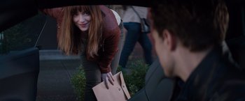 Movie still from “Fifty Shades of Grey” (2015), directed by Sam Taylor-Johnson – A young woman holding onto a paper bag while standing next to a man; Medium shot, Over the shoulder angle