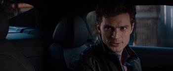 Movie still from “Fifty Shades of Grey” (2015), directed by Sam Taylor-Johnson – A person sitting in a car; Close Up shot, Over the shoulder angle