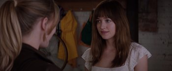 Movie still from “Fifty Shades of Grey” (2015), directed by Sam Taylor-Johnson – A young woman with long brown hair standing next to another woman; Close Up shot, Over the shoulder angle