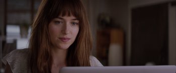 Movie still from “Fifty Shades of Grey” (2015), directed by Sam Taylor-Johnson – A beautiful young lady sitting in front of a laptop computer; Close Up shot, Over the shoulder angle