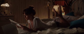 Movie still from “Fifty Shades of Grey” (2015), directed by Sam Taylor-Johnson – A woman laying on a bed looking at her cell phone; Wide shot, High angle