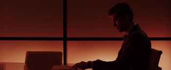 Movie still from “Fifty Shades of Grey” (2015), directed by Sam Taylor-Johnson – A man sitting at a desk in front of an open laptop computer; Medium shot, Over the shoulder angle