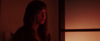 Movie still from “Fifty Shades of Grey” (2015), directed by Sam Taylor-Johnson – A woman with long brown hair is looking at the camera; Close Up shot, Over the shoulder angle