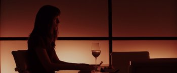 Movie still from “Fifty Shades of Grey” (2015), directed by Sam Taylor-Johnson – A woman sitting in front of a laptop next to a glass of wine; Medium shot, Over the shoulder angle