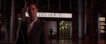 Movie still from “Fifty Shades of Grey” (2015), directed by Sam Taylor-Johnson – A man standing in front of a building at night; Medium shot, Low angle