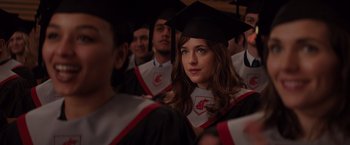 Movie still from “Fifty Shades of Grey” (2015), directed by Sam Taylor-Johnson – A woman in a cap and gown is looking at the camera; Close Up shot, Over the shoulder angle