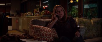 Movie still from “Fifty Shades of Grey” (2015), directed by Sam Taylor-Johnson – A woman sitting on a couch talking on a phone; Medium shot, Over the shoulder angle