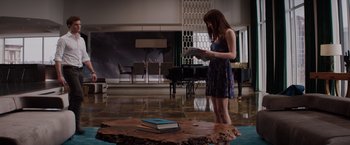 Movie still from “Fifty Shades of Grey” (2015), directed by Sam Taylor-Johnson – A woman standing in front of an open book on top of a tree trunk; Wide shot, High angle