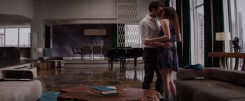 Movie still from “Fifty Shades of Grey” (2015), directed by Sam Taylor-Johnson – A man and a woman kissing in front of a piano; Wide shot, High angle