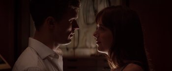 Movie still from “Fifty Shades of Grey” (2015), directed by Sam Taylor-Johnson – A man and a woman looking at each other in the dark; Close Up shot, Over the shoulder angle