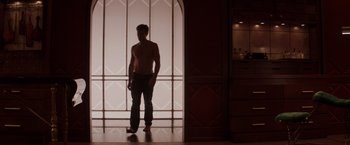 Movie still from “Fifty Shades of Grey” (2015), directed by Sam Taylor-Johnson – A man standing in front of an arched window; Wide shot, Low angle
