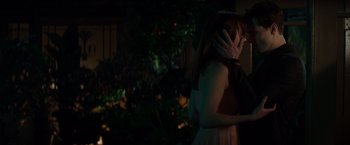 Movie still from “Fifty Shades of Grey” (2015), directed by Sam Taylor-Johnson – A man and a woman embracing in a dark room; Medium shot, Over the shoulder angle