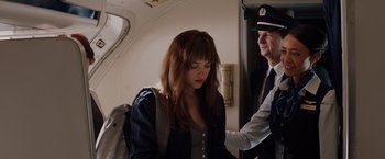 Movie still from “Fifty Shades of Grey” (2015), directed by Sam Taylor-Johnson – A woman is standing next to an officer; Medium shot, Over the shoulder angle