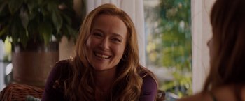 Movie still from “Fifty Shades of Grey” (2015), directed by Sam Taylor-Johnson – A woman with long red hair smiling for the camera; Close Up shot, Over the shoulder angle