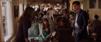 Movie still from “Fifty Shades of Grey” (2015), directed by Sam Taylor-Johnson – A woman sitting on top of a couch in a room; Wide shot, Over the shoulder angle