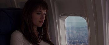 Movie still from “Fifty Shades of Grey” (2015), directed by Sam Taylor-Johnson – A woman sitting on top of an airplane looking out the window; Close Up shot, Over the shoulder angle