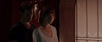 Movie still from “Fifty Shades of Grey” (2015), directed by Sam Taylor-Johnson – A man and a woman standing next to each other in a room; Medium shot, Over the shoulder angle