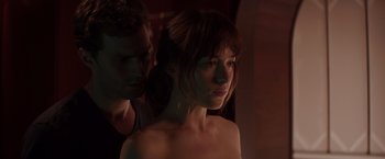 Movie still from “Fifty Shades of Grey” (2015), directed by Sam Taylor-Johnson – A man standing next to a woman in a dark room; Close Up shot, Over the shoulder angle
