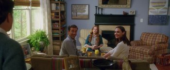 Movie still from “Keeping Up with the Joneses” (2016), directed by Greg Mottola – A group of people sitting at a table in a living room; Wide shot, Over the shoulder angle