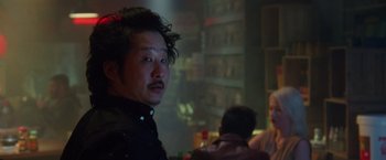 Movie still from “Keeping Up with the Joneses” (2016), directed by Greg Mottola – A man in a black shirt is in a dark room; Close Up shot, Over the shoulder angle