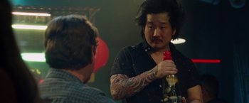 Movie still from “Keeping Up with the Joneses” (2016), directed by Greg Mottola – A man holding a bottle of beer in front of another man; Close Up shot, Over the shoulder angle