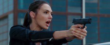 Movie still from “Keeping Up with the Joneses” (2016), directed by Greg Mottola – A beautiful woman holding a gun in her hand; Close Up shot, Over the shoulder angle