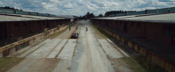 Movie still from “Keeping Up with the Joneses” (2016), directed by Greg Mottola – A car driving down a dirt road next to a group of motorcycles; Extreme Wide shot, High angle